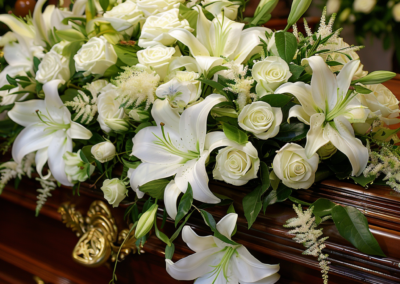 White Lily and Rose Coffin Spray sitting on a funeral casket